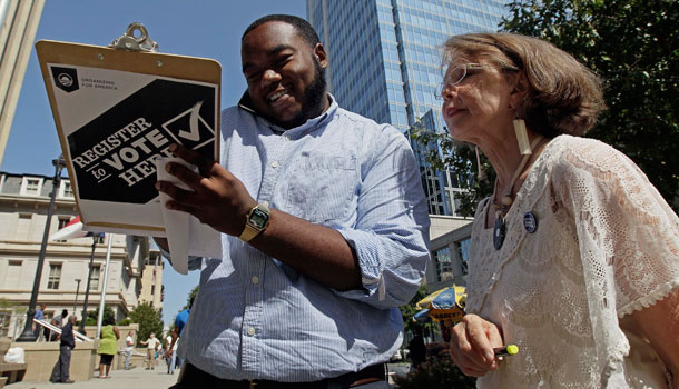 In this photo taken Sept. 26, 2012, campaign volunteer Barbara Smalley-McMahan, right, registers 18-year-old Walter Woody III to vote for the first time in Raleigh, N.C. /AP Photo/Gerry Broome